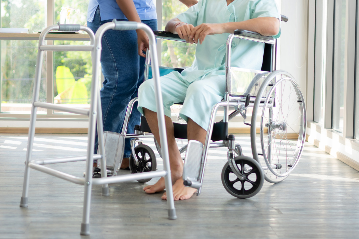 patient sat in wheelchair about to transition to using a Zimmer frame with the help of another person