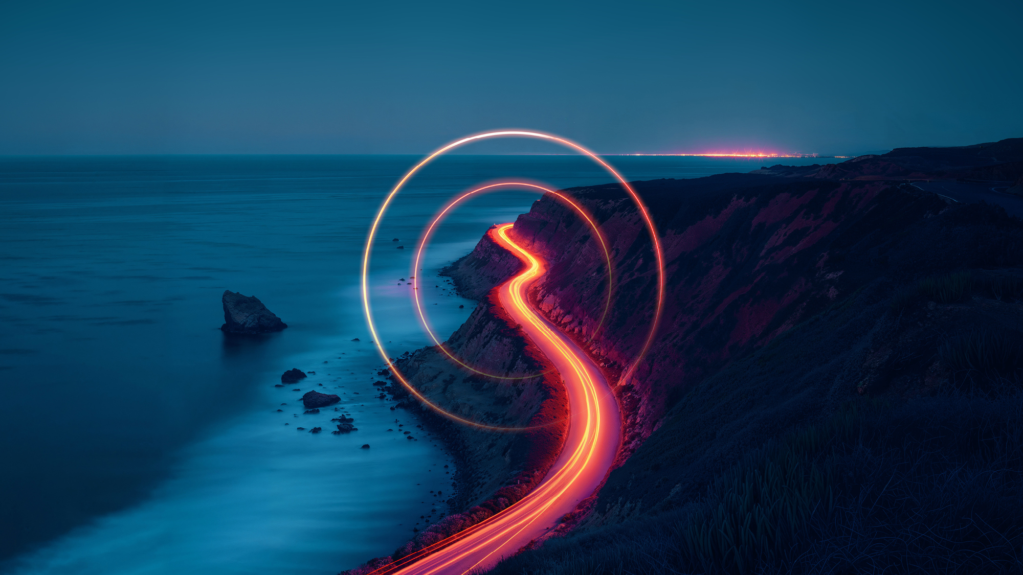 Light trail photography of cars along road near the sea at night with light trail 'O' overlayed