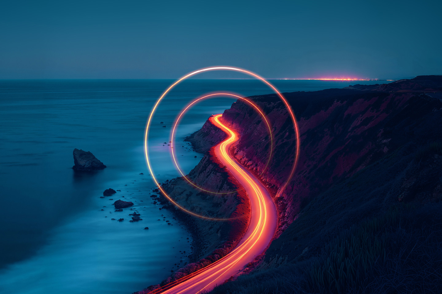 Light trail photography of cars along road near the sea at night with light trail 'O' overlayed