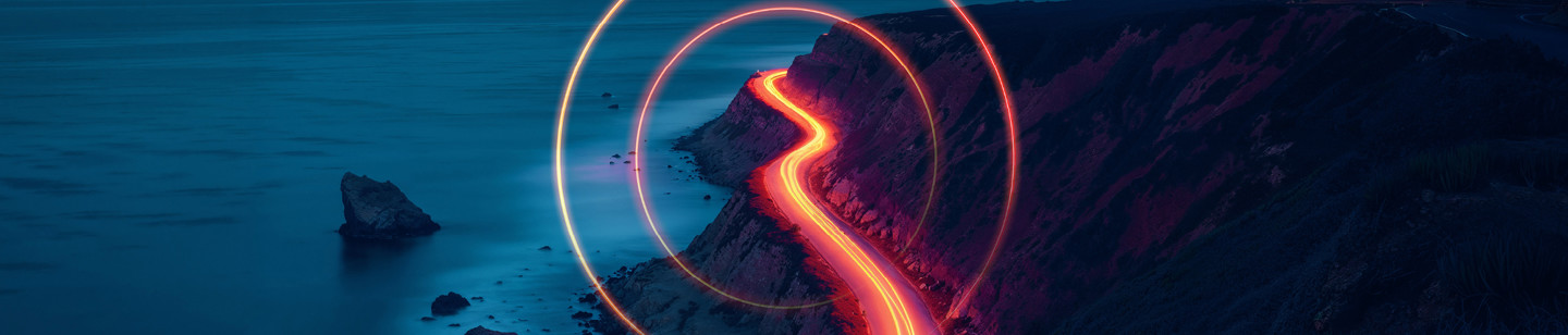 Light trail photography of cars along road near the sea at night with light trail 'O' overlayed