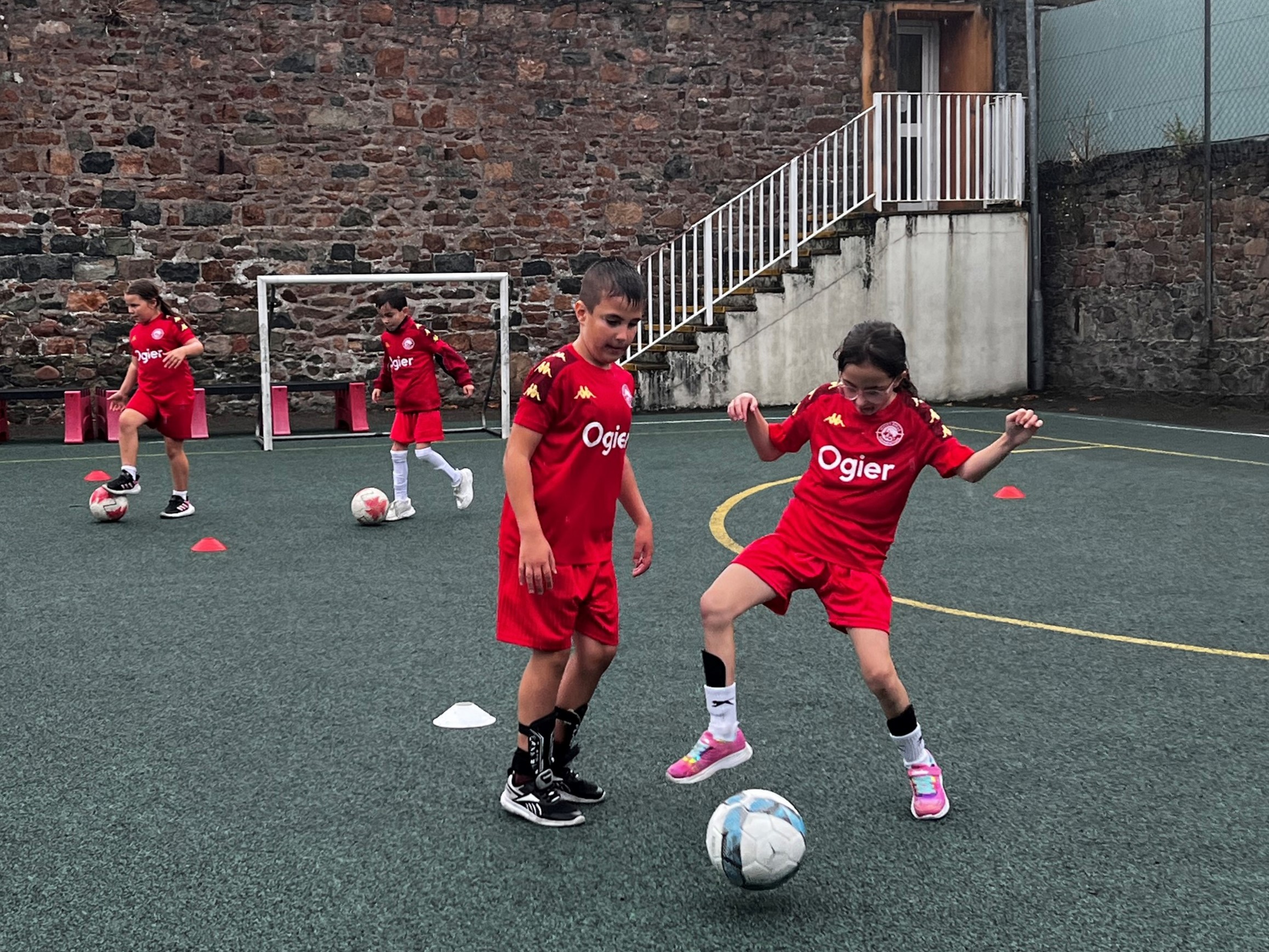 children in Ogier-branded football kits practise skills on an outdoor pitch as part of Jersey Bulls Community Foundation’s new after-school support programm