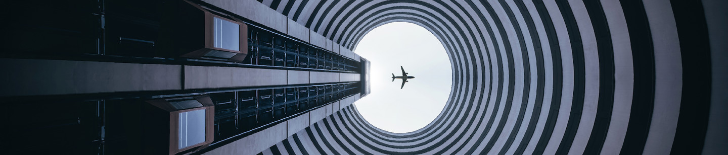 Tunnel pointing up towards an airplane in the sky