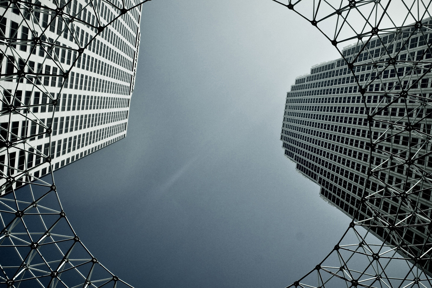 ground view of high rise buildings with barbed wire overlayed forming an O