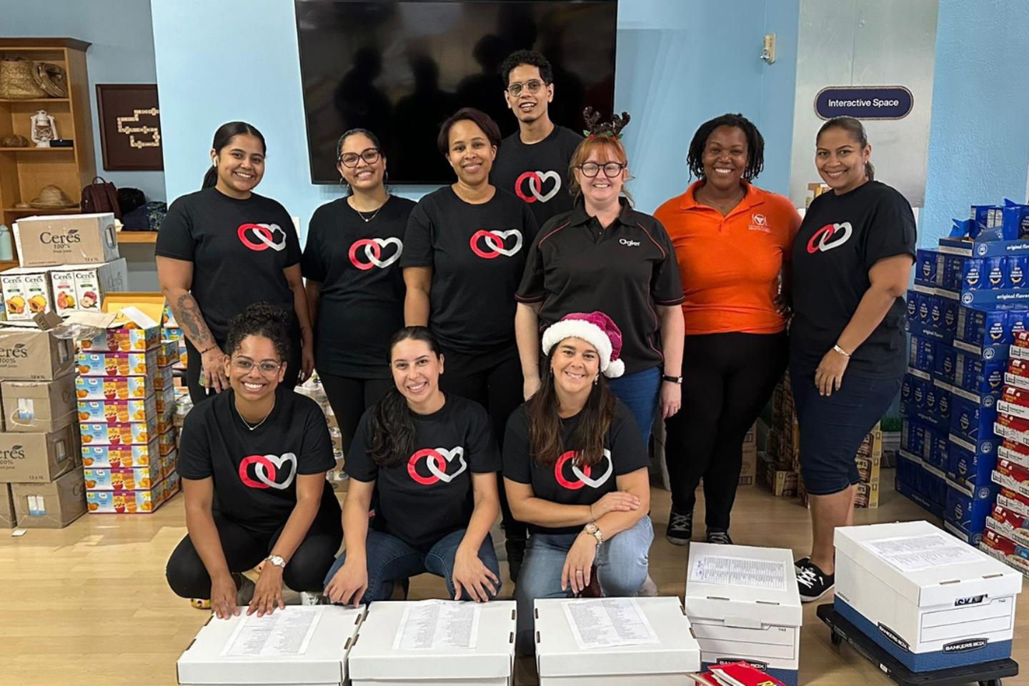 volunteers in Ogier shirts and Meals on Wheels staff assemble and pack 225 Christmas grocery boxes for delivery to vulnerable residents in Grand Cayman.